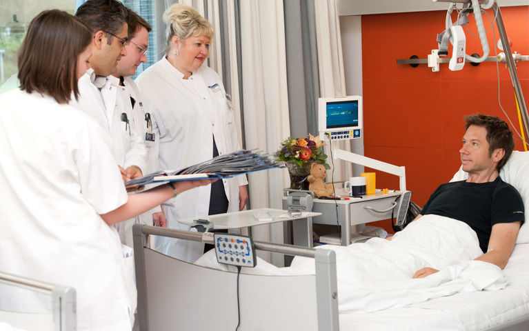 Patient_in_bed_with_medical_team_Heidelberg